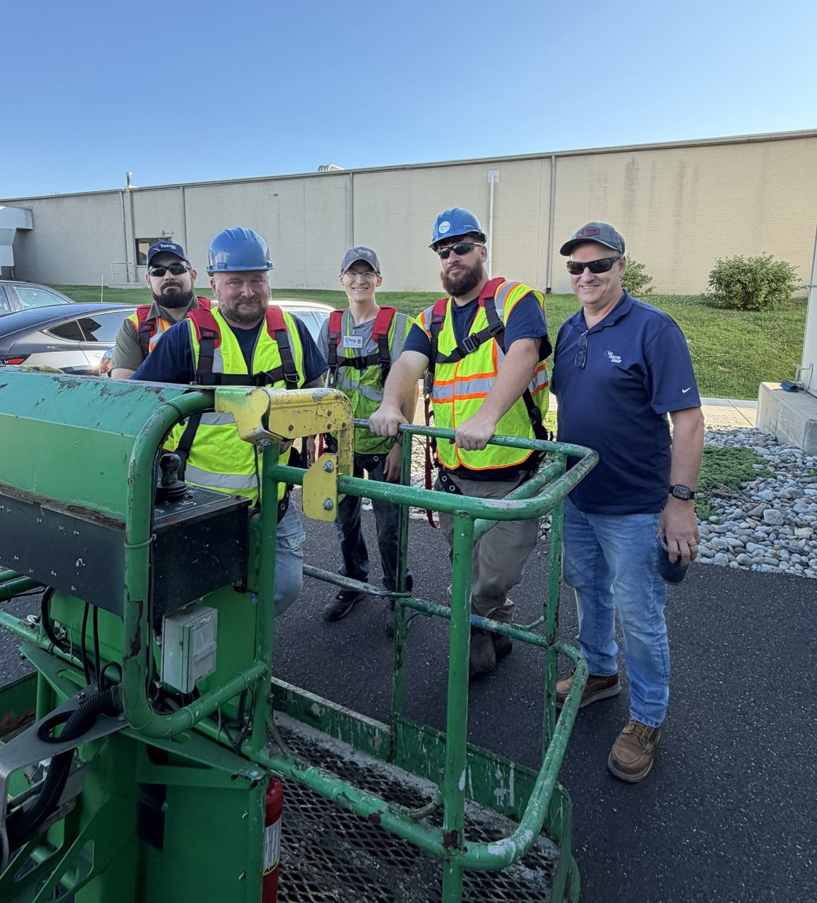 Five Tustin field team members wearing safety equipment beside a lift